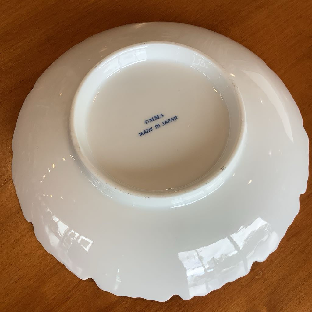 White ceramic plate with scalloped edge on a wooden surface, featuring 'Corma Made in Japan' text.