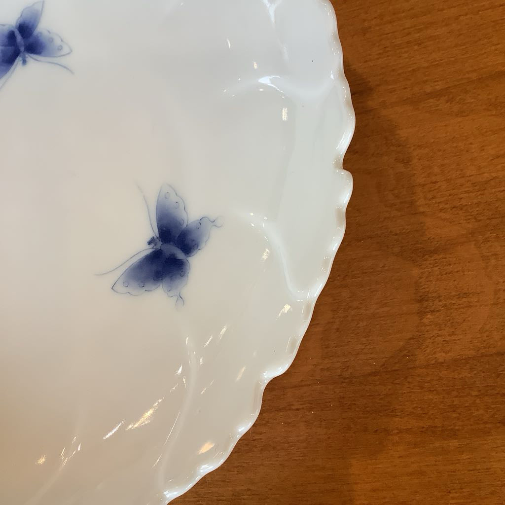 White ceramic plate with blue butterfly designs on a wooden surface