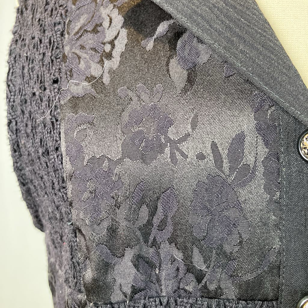 Black vest with floral pattern on a mannequin against a gray background