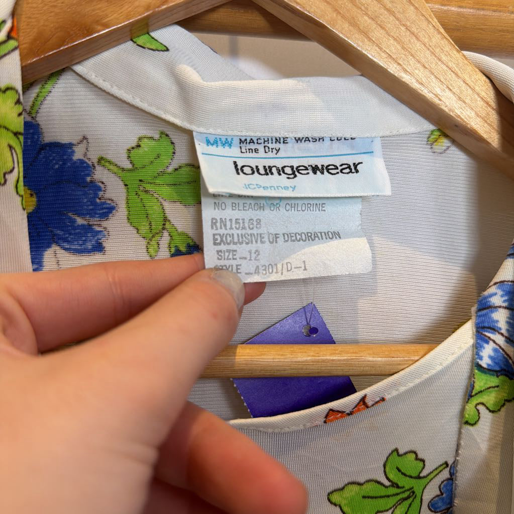 Clothing label on a floral-patterned garment with a hand holding the hanger.