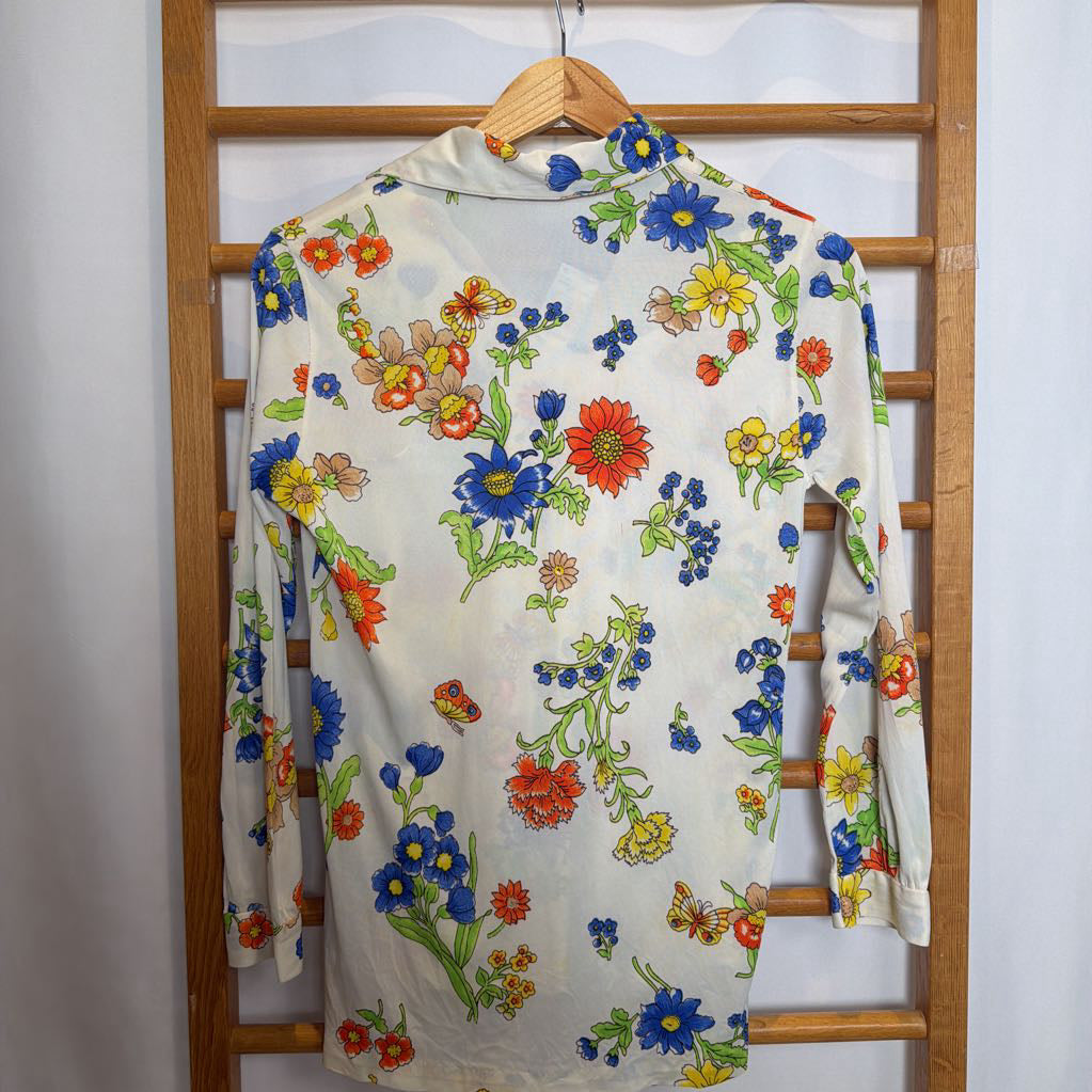 Floral-patterned shirt on a wooden hanger against a white wall