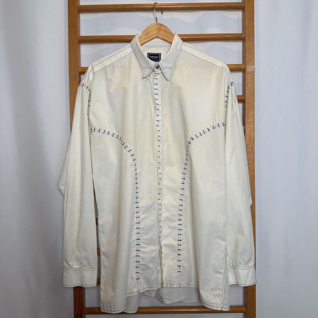 White shirt with black stitching on a wooden hanger against a white background