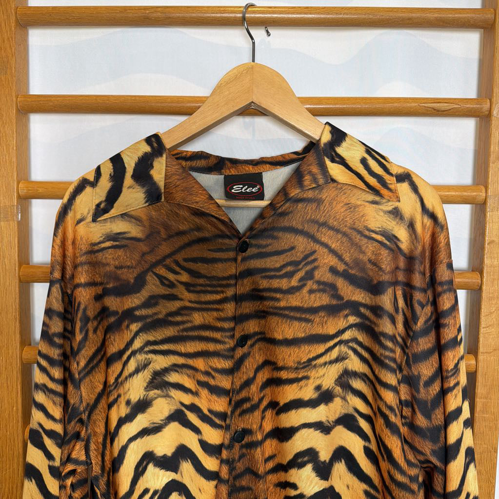 Tiger patterned shirt on a hanger with a visible brand label against a wooden background.