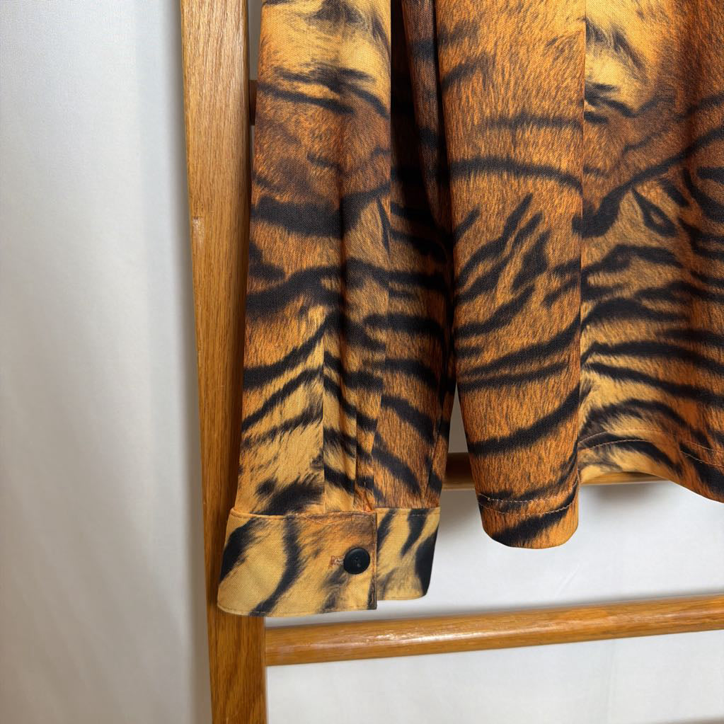 Tiger-striped shirt hanging on a wooden rack against a white wall