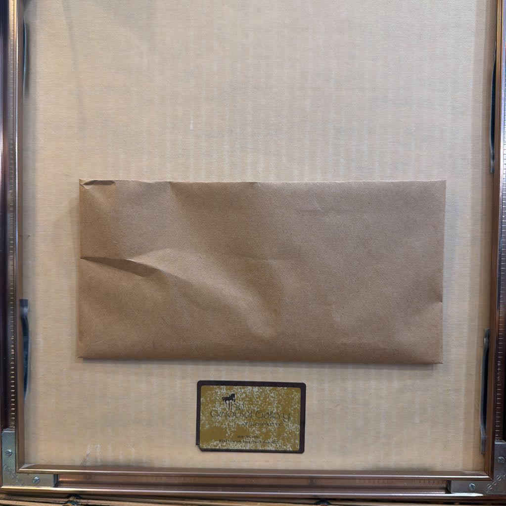 Framed brown envelope with a gold label on a textured beige background