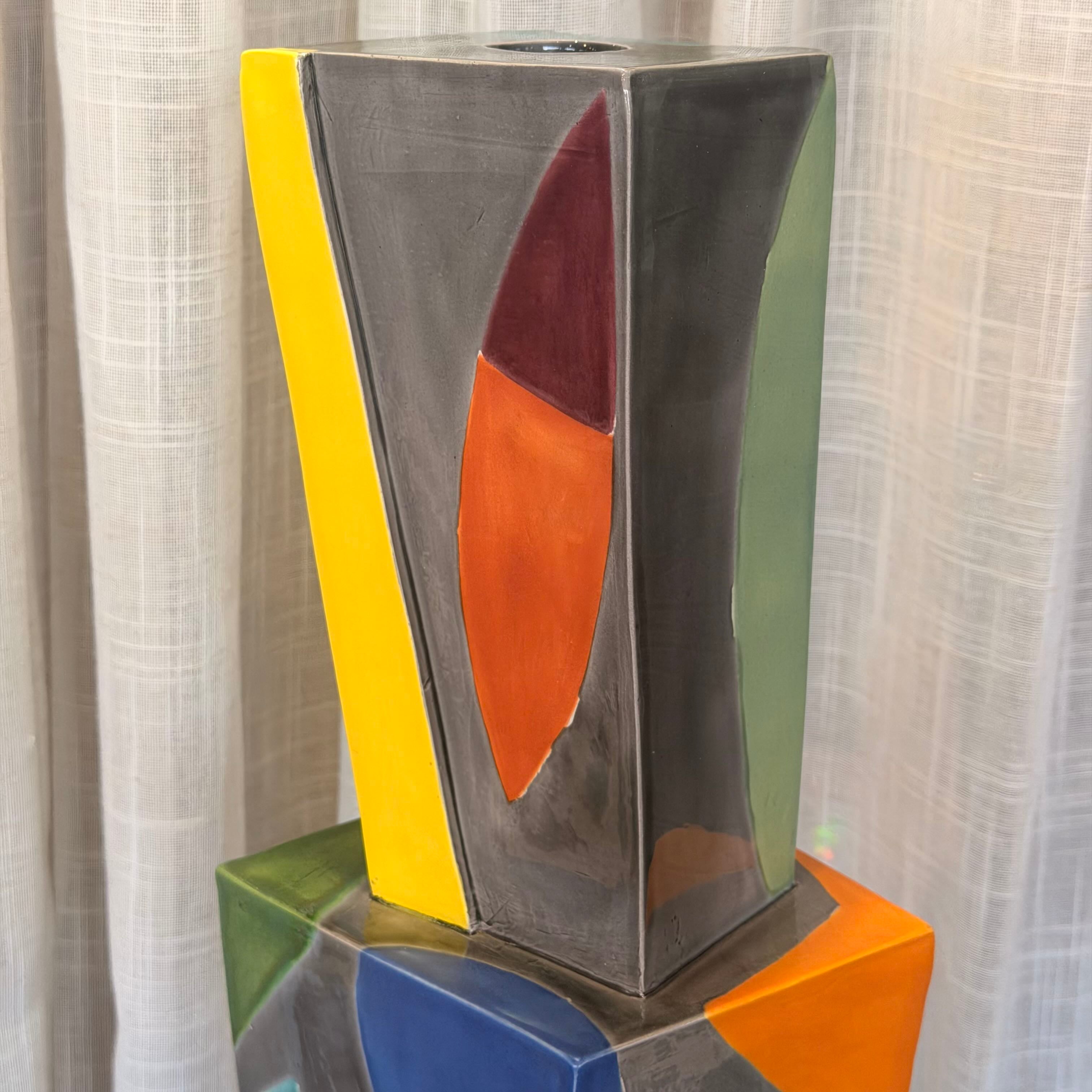 Abstract art piece with geometric shapes on a stand against a neutral background