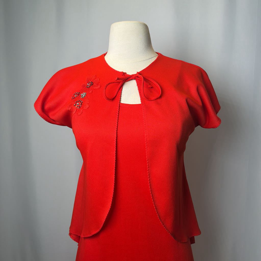 Red dress with floral embroidery on a mannequin against a gray background