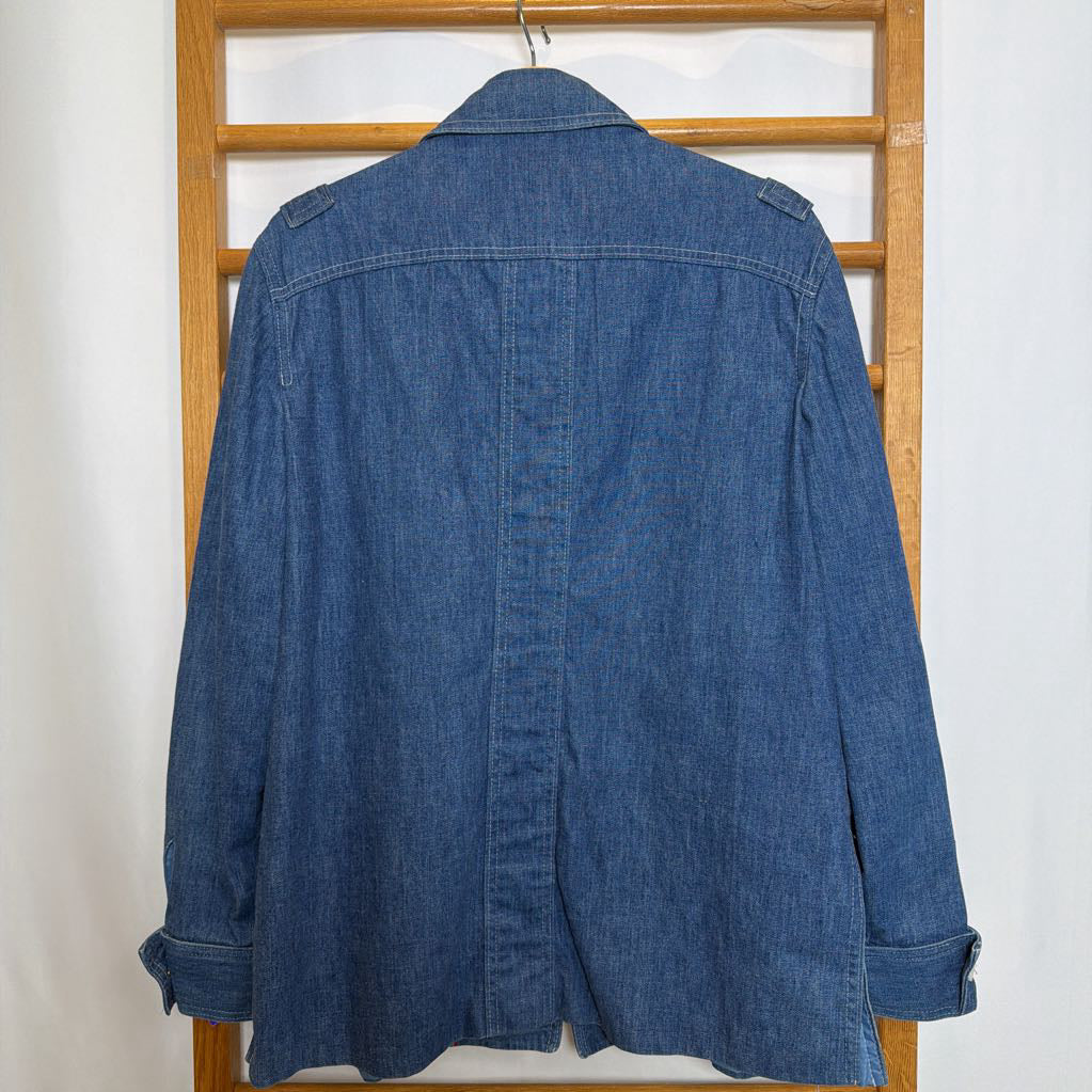 Blue denim jacket on a wooden hanger against a white wall