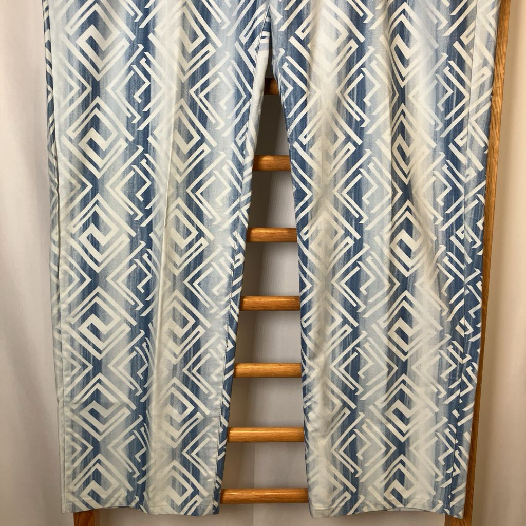 Blue and white patterned curtains with a wooden ladder in front on a neutral background