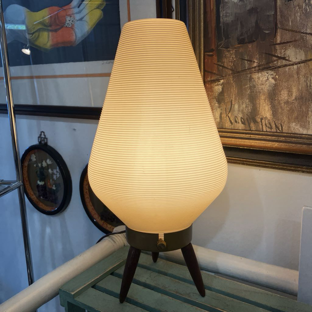 Vintage-style lamp with a textured shade on a wooden base in a room setting.