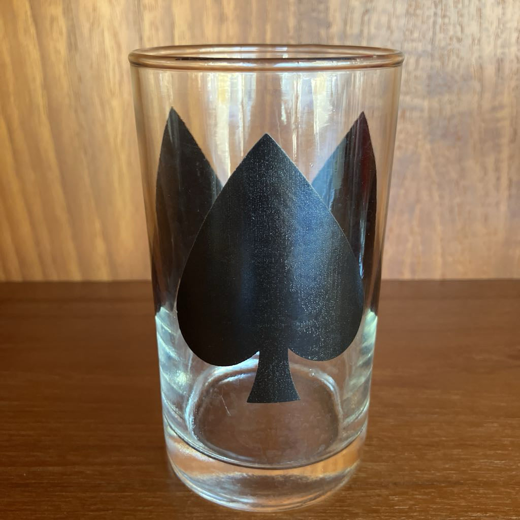 Clear glass with black spade symbol on a wooden surface