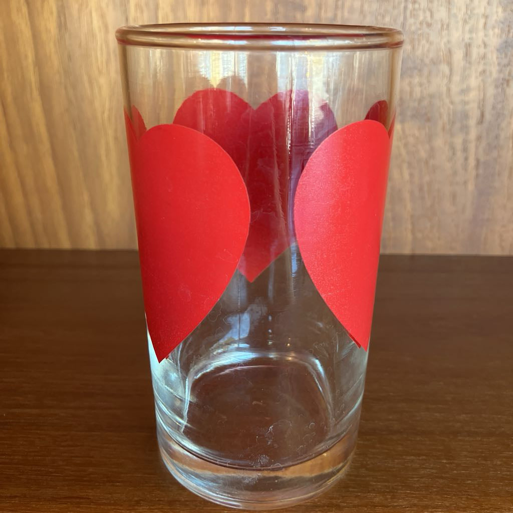 Clear glass with red heart designs on a wooden surface