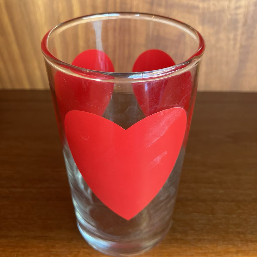 Clear glass with a red heart-shaped design on a wooden surface