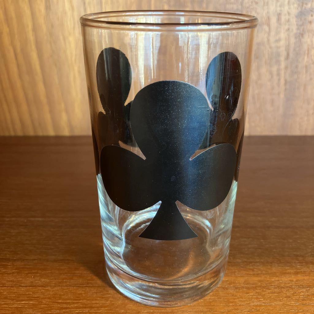 Clear glass with black club symbol on a wooden surface