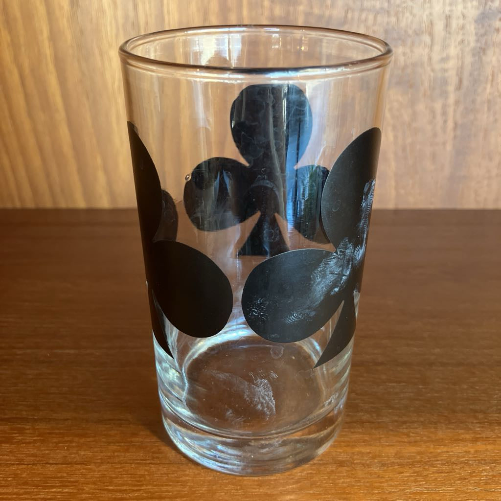 Clear glass with black club patterns on a wooden surface