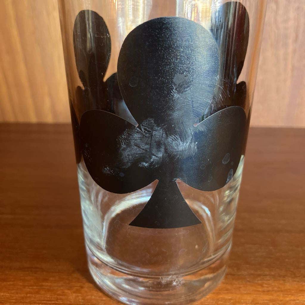Clear glass with black club symbol on a wooden surface
