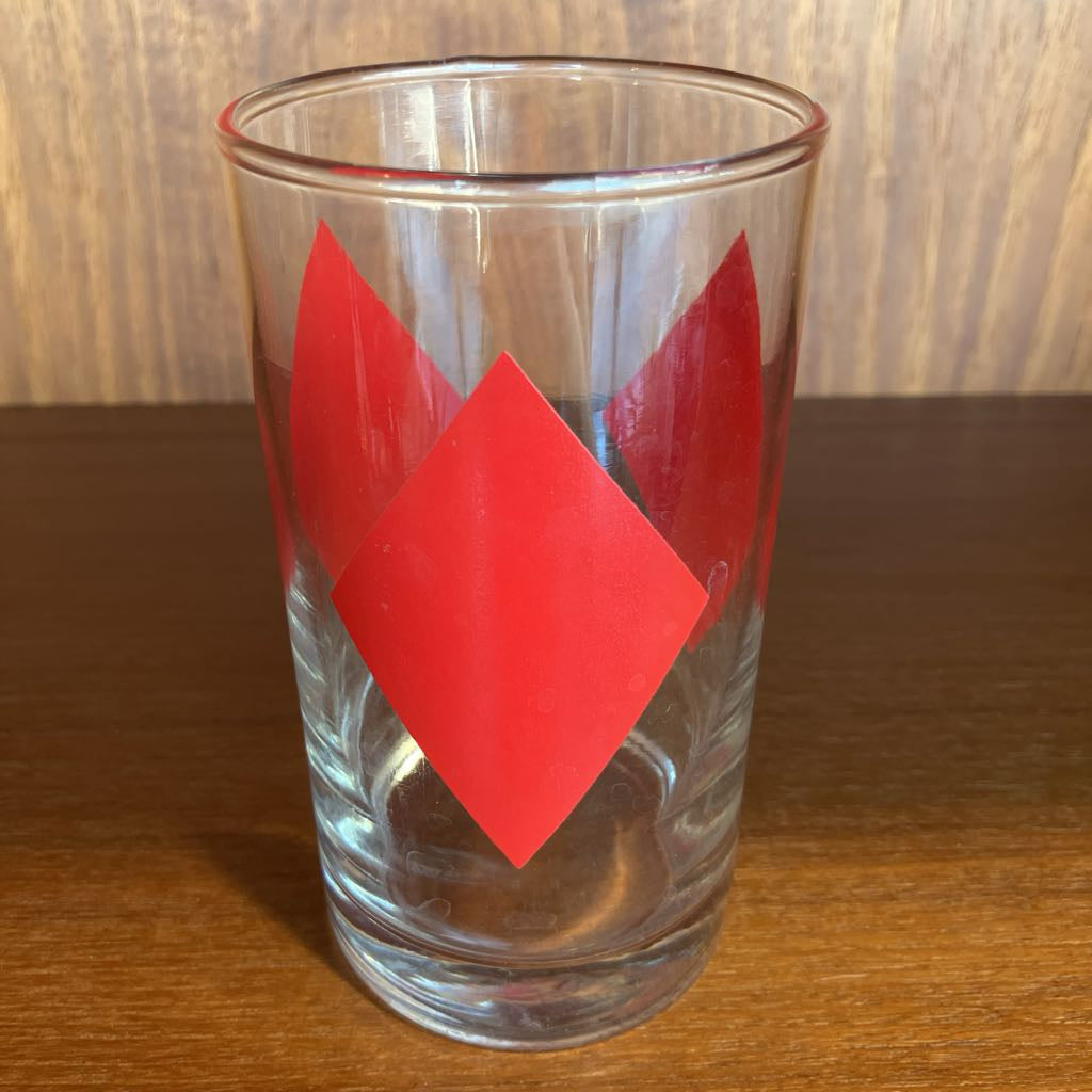 Clear glass with red diamond-shaped designs on a wooden surface