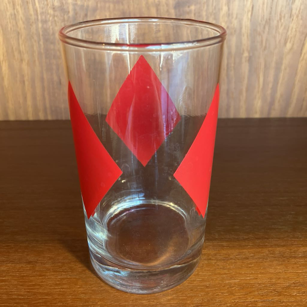 Clear glass with red diamond shapes on a wooden surface
