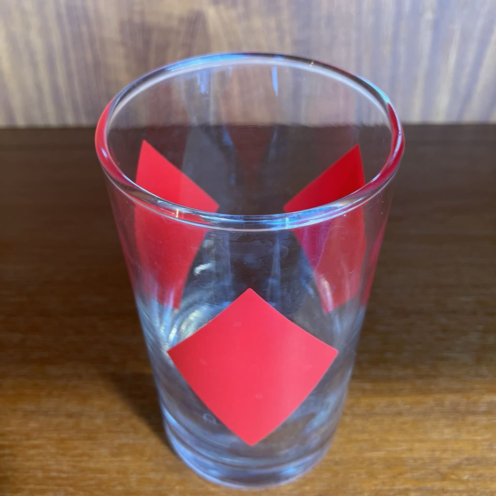 Clear glass with red diamond-shaped design on a wooden surface