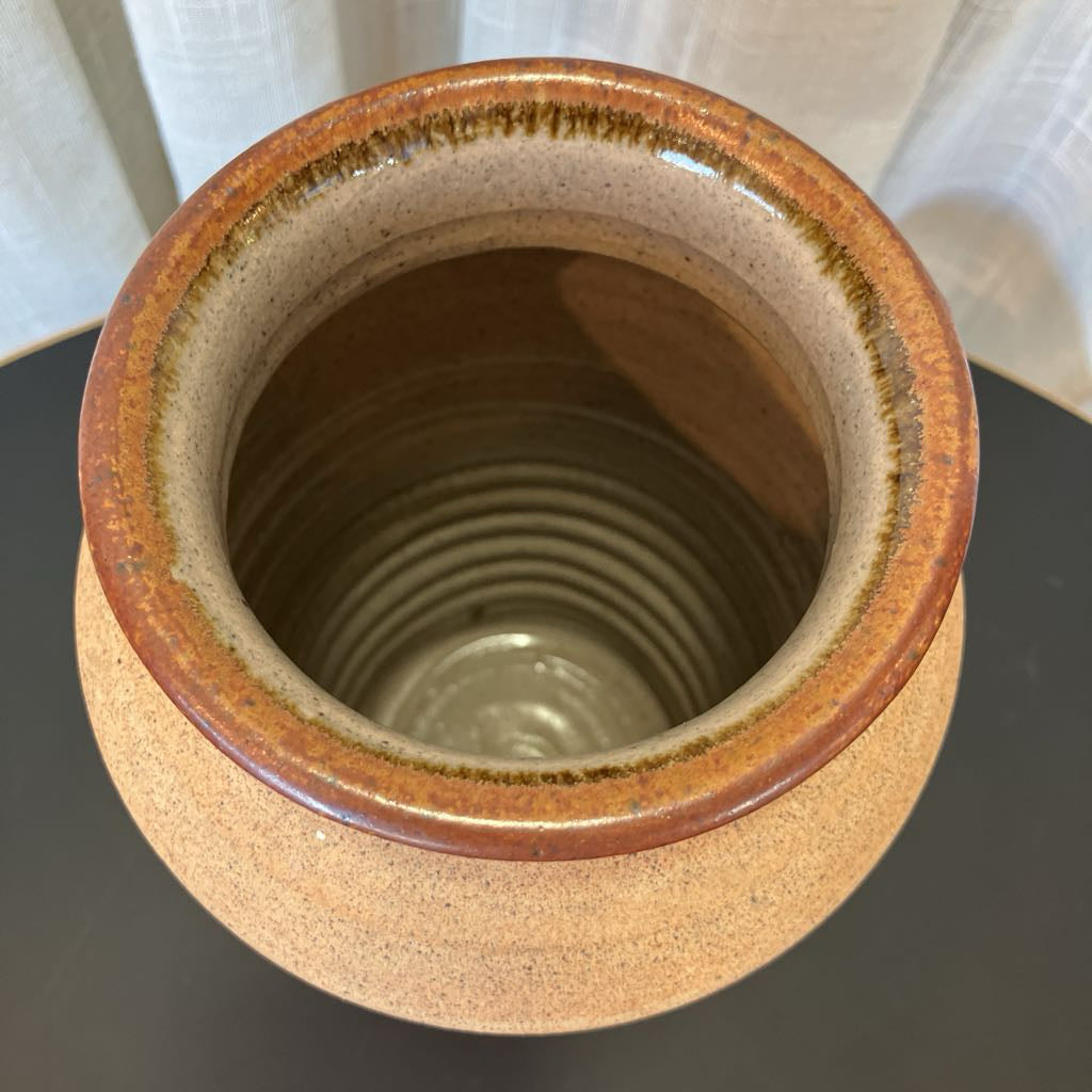Ceramic vase with brown rim and interior on a dark surface