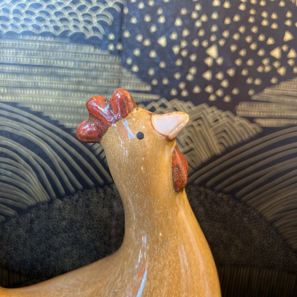 Ceramic chicken figurine on a textured surface