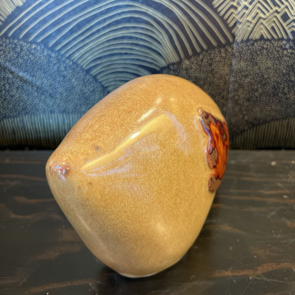 Brown ceramic object with a textured surface on a dark surface