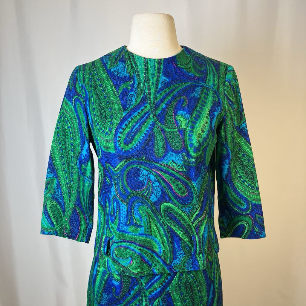 Mannequin wearing a green and blue patterned dress against a neutral background