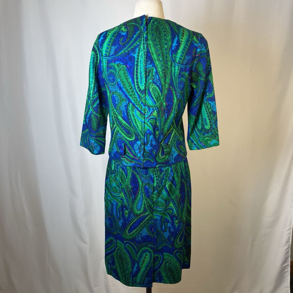 Green and blue patterned dress on a mannequin against a plain background