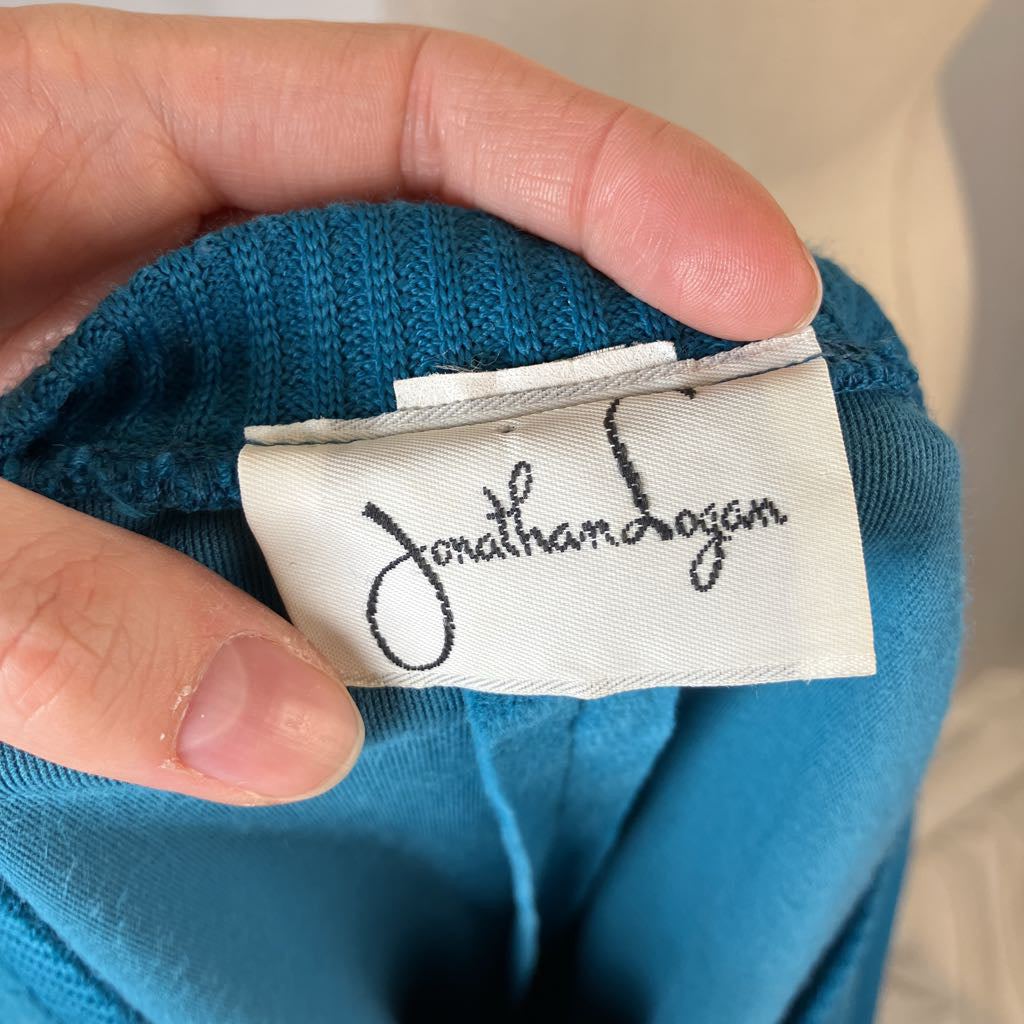 Hand holding a blue garment with a 'Jonathan Logan' label.