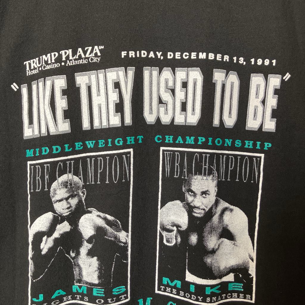 Close-up of a black graphic t-shirt featuring a printed design for the 1991 Trump Plaza Middleweight Championship fight between James 'The Great White Hurricane' Jackson and Mike 'The Body Snatcher' Henderson. The design includes white and teal text and black-and-white boxing portraits of both fighters.