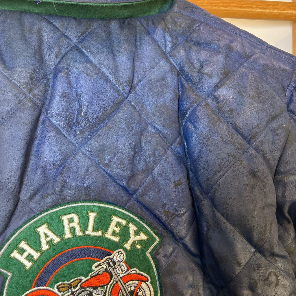 Quilted blue jacket with a Harley Davidson patch on a wooden surface