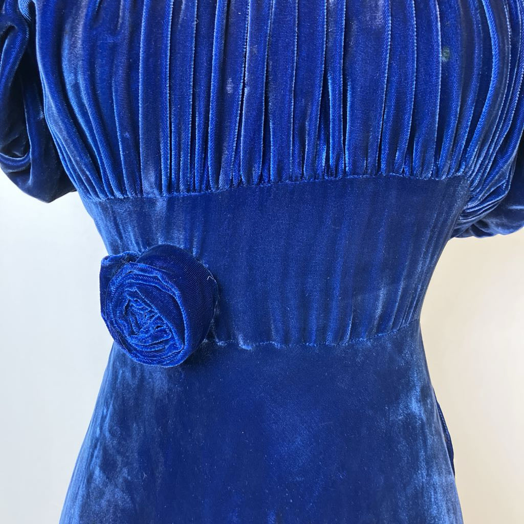 Close-up of a blue velvet dress with a floral detail on a white background