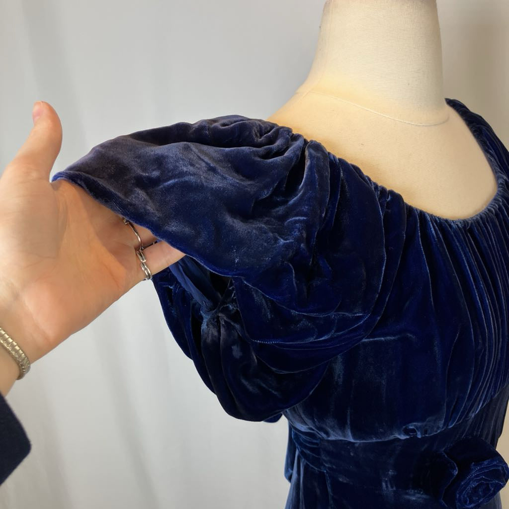 Navy blue velvet dress on a mannequin with a hand touching the fabric.