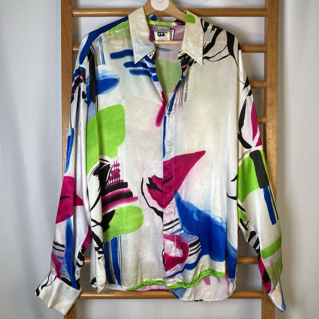 Colorful abstract patterned shirt on a wooden hanger against a white wall