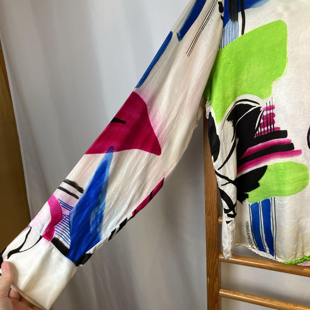 Colorful patterned fabric draped over a wooden hanger against a white background