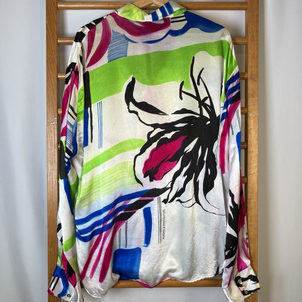 Colorful shirt with floral design on a wooden hanger against a white wall