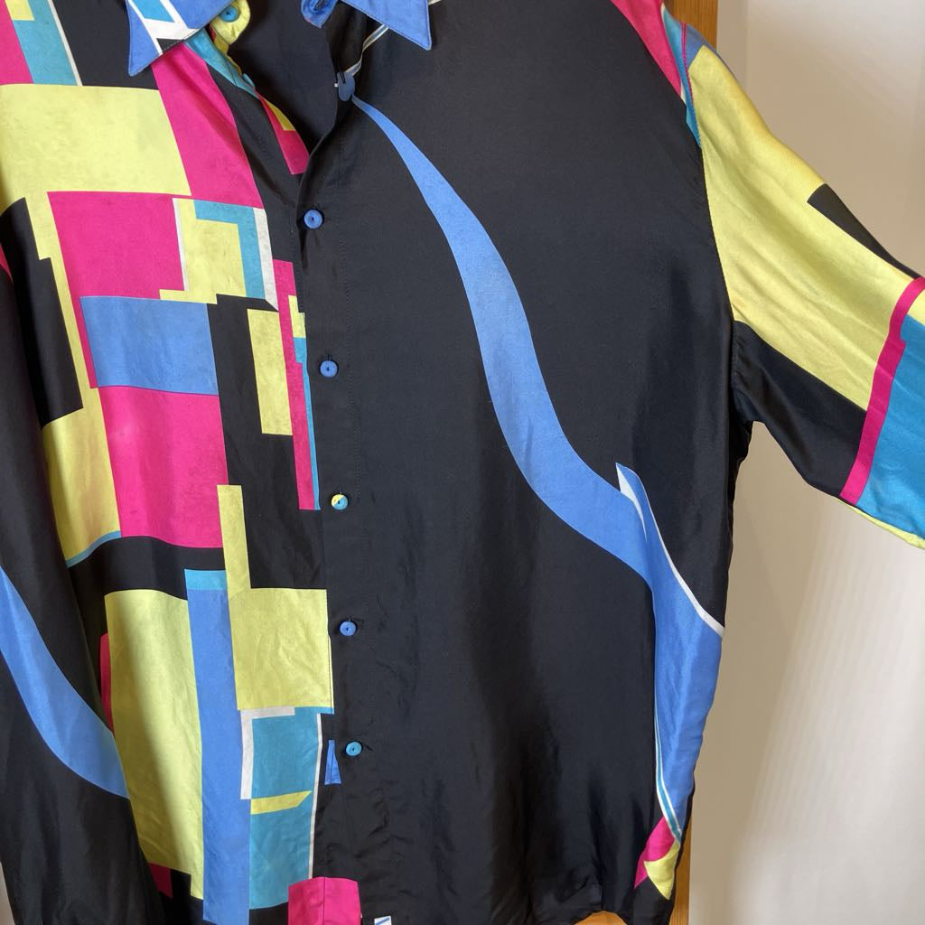 Colorful geometric-patterned shirt on a mannequin against a neutral background