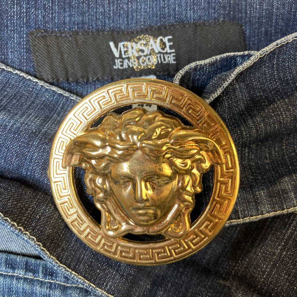 Gold belt buckle with Medusa head design on Versace jeans.