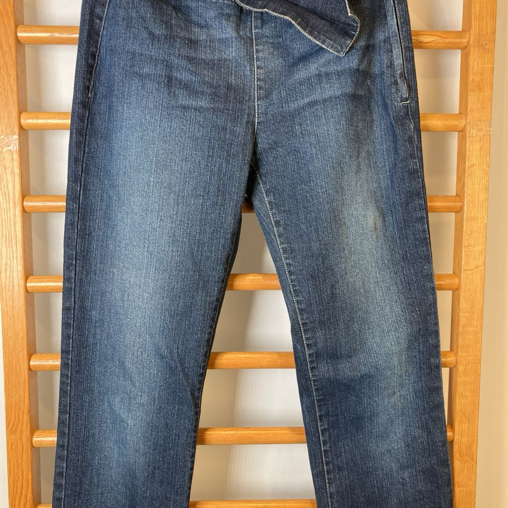 Blue jeans hanging on a wooden rack against a white wall