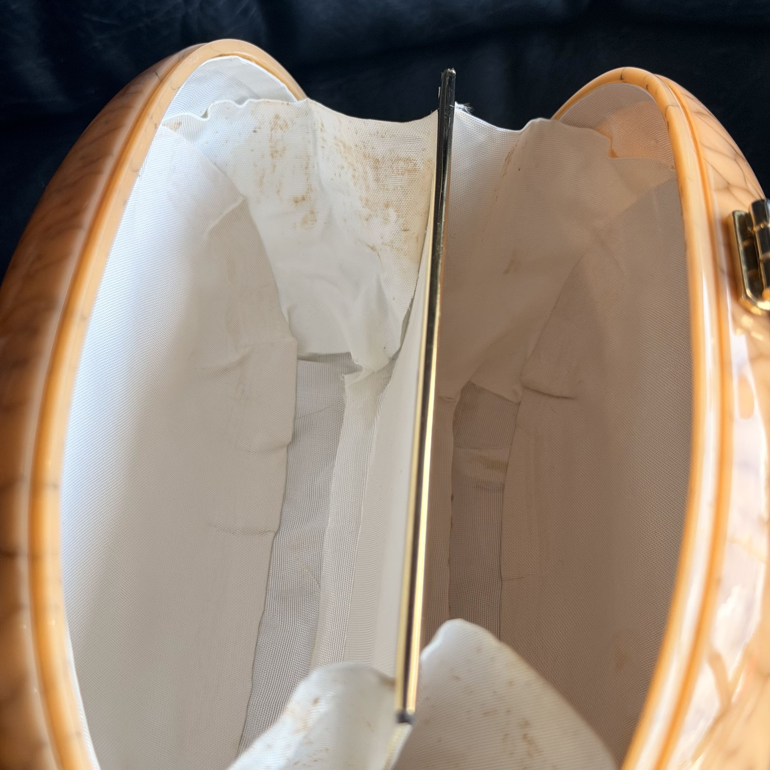 Close-up of a white shoe with a gold lace in an open wooden shoebox.