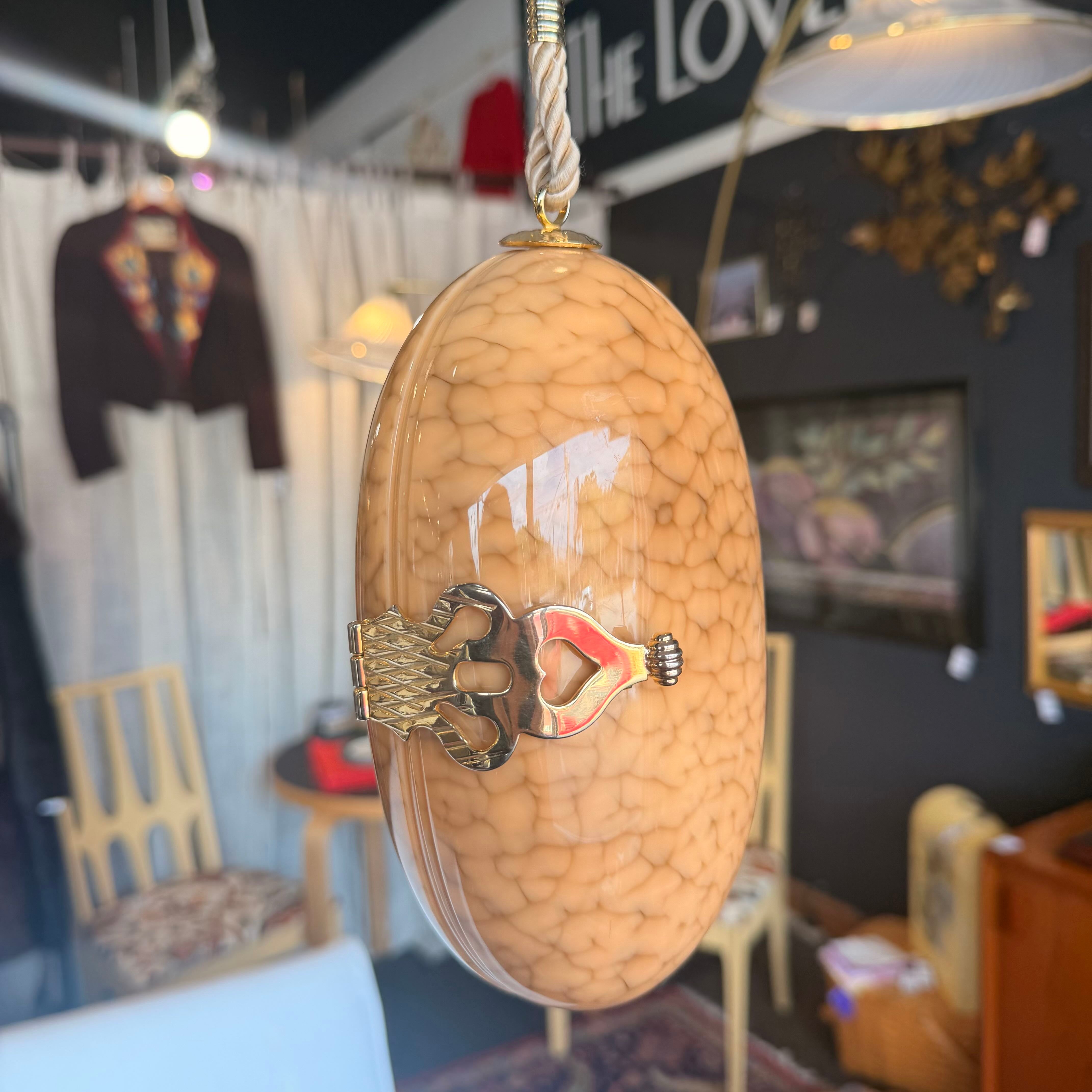 Decorative egg-shaped object with a design of a bear and a face, hanging in a room with furniture and decor.