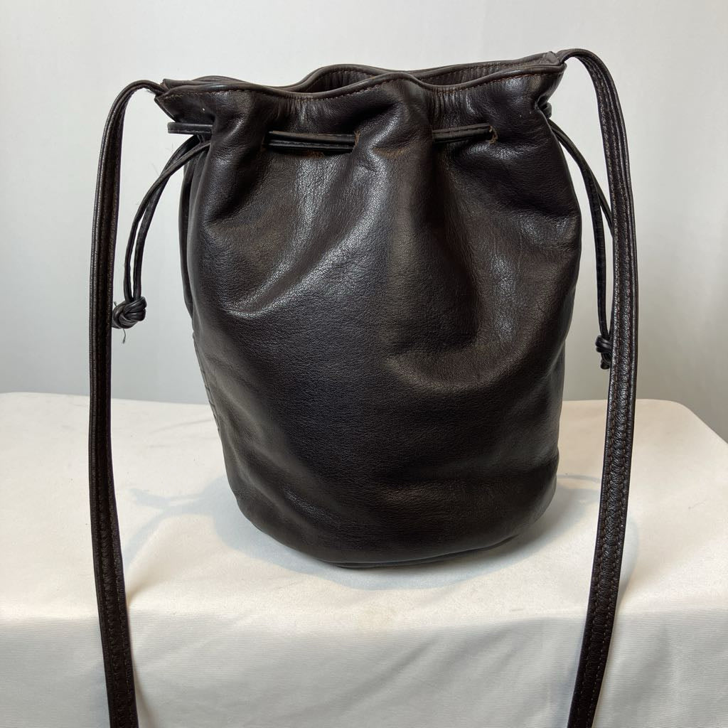 Black leather drawstring bag on a white surface with a light gray background