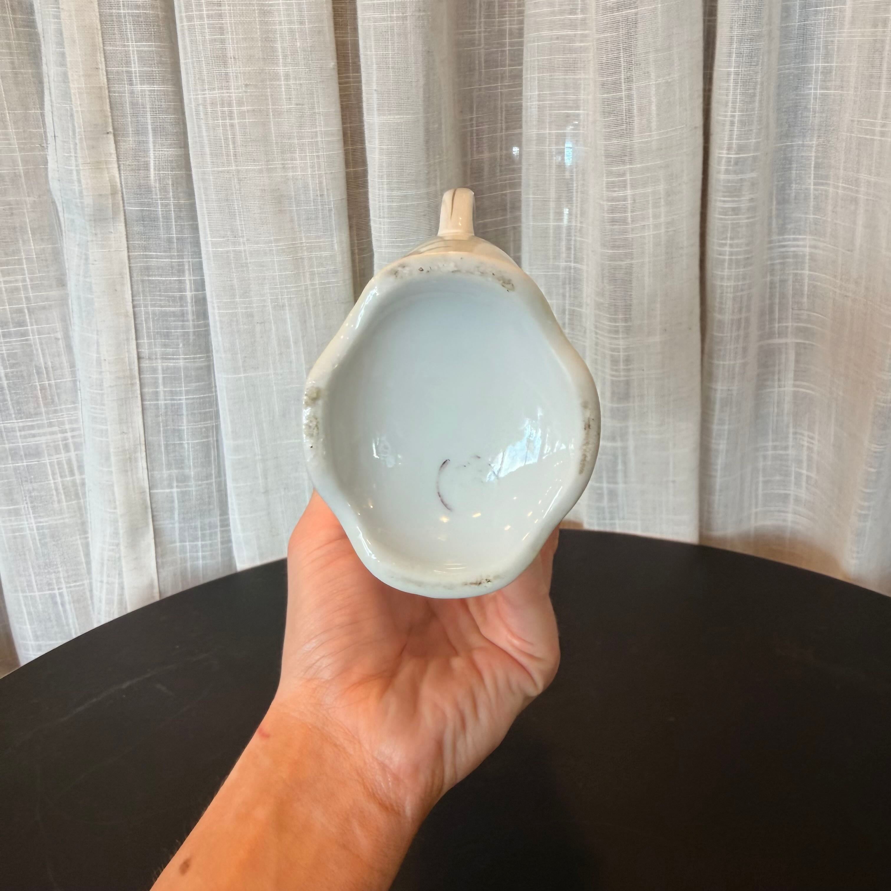 Hand holding a small ceramic bowl against a neutral background