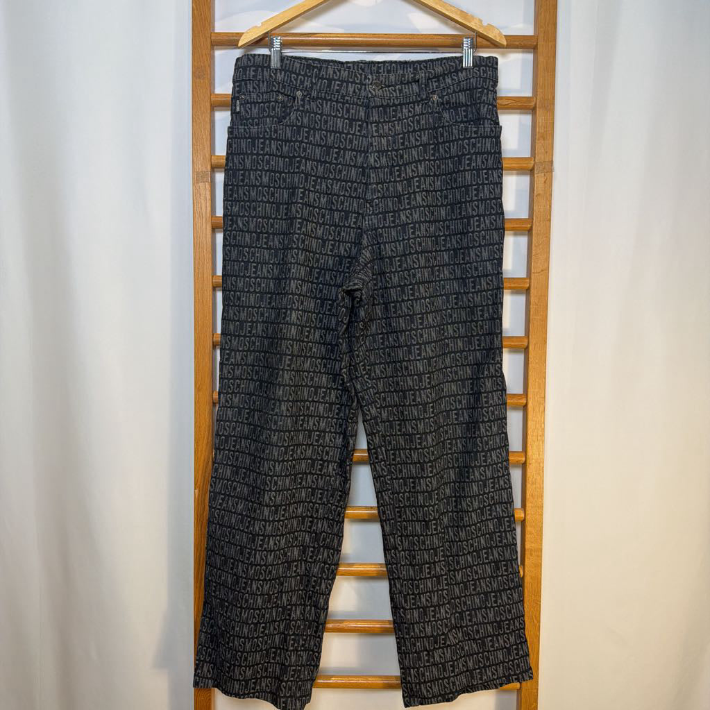 Black patterned pants hanging on a wooden rack against a white background