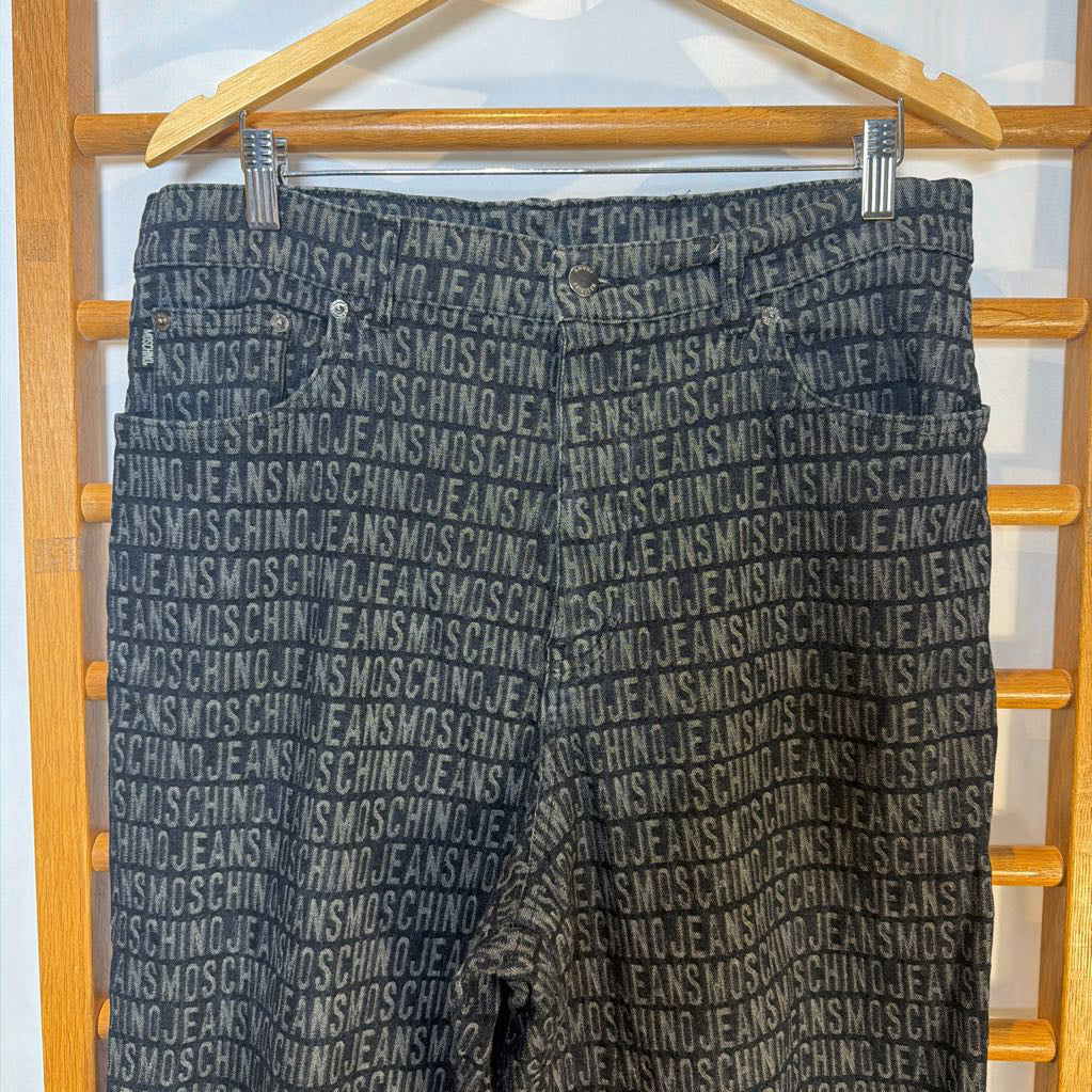 Gray pants with Moschino branding on a wooden hanger against a white background