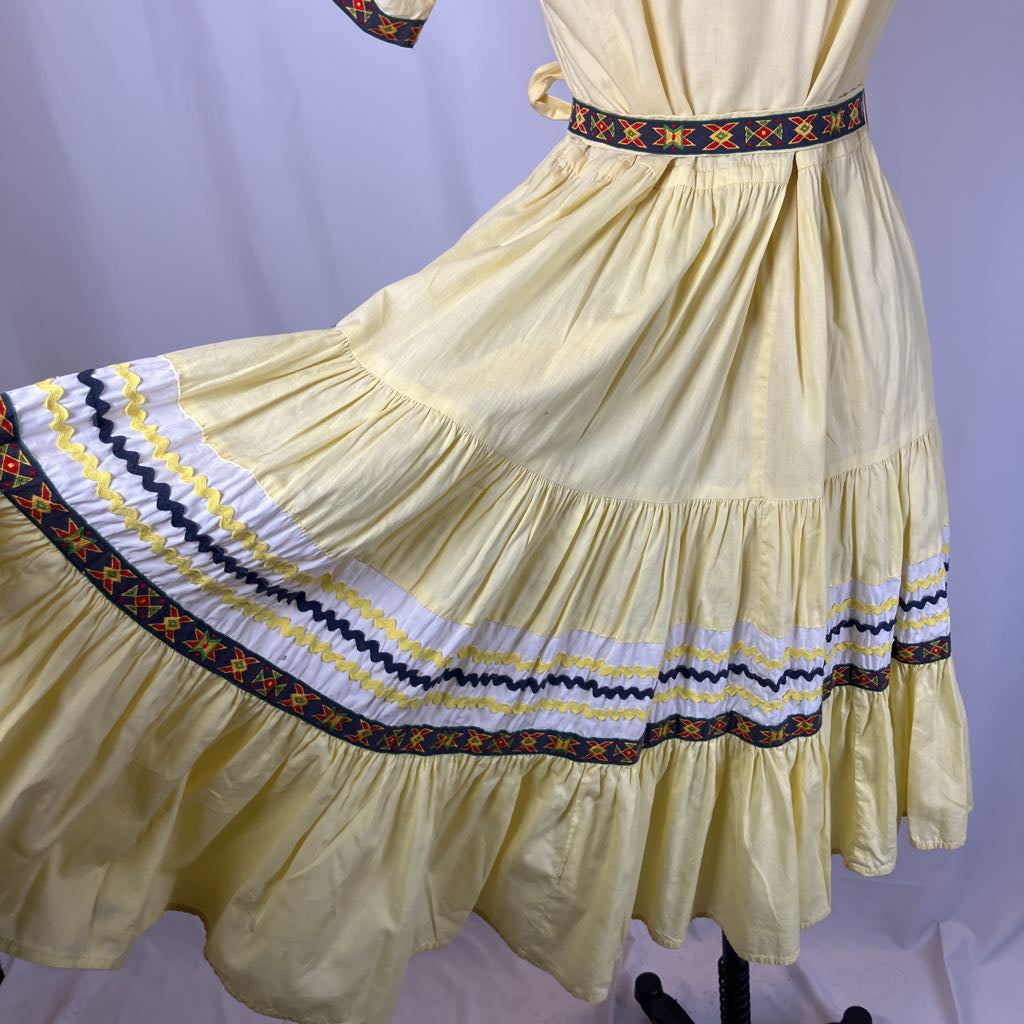 Yellow dress with decorative hem on a mannequin against a purple background