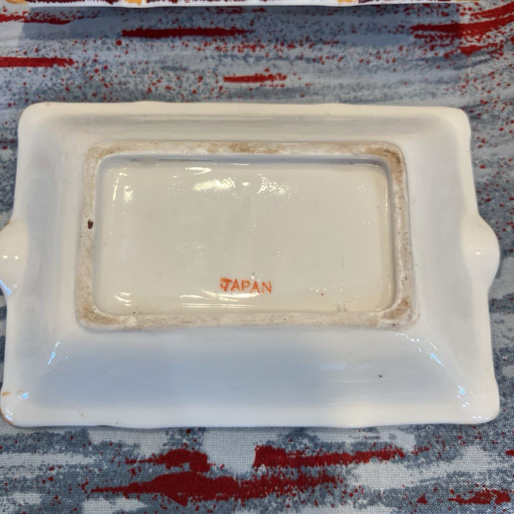 White ceramic dish with 'Japan' text on a patterned surface
