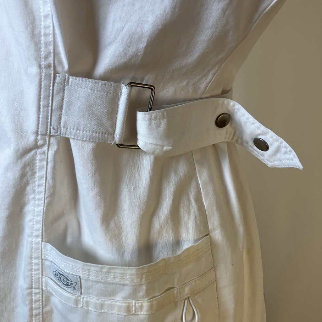 Close-up of a beige jacket with a belt and button details on a neutral background