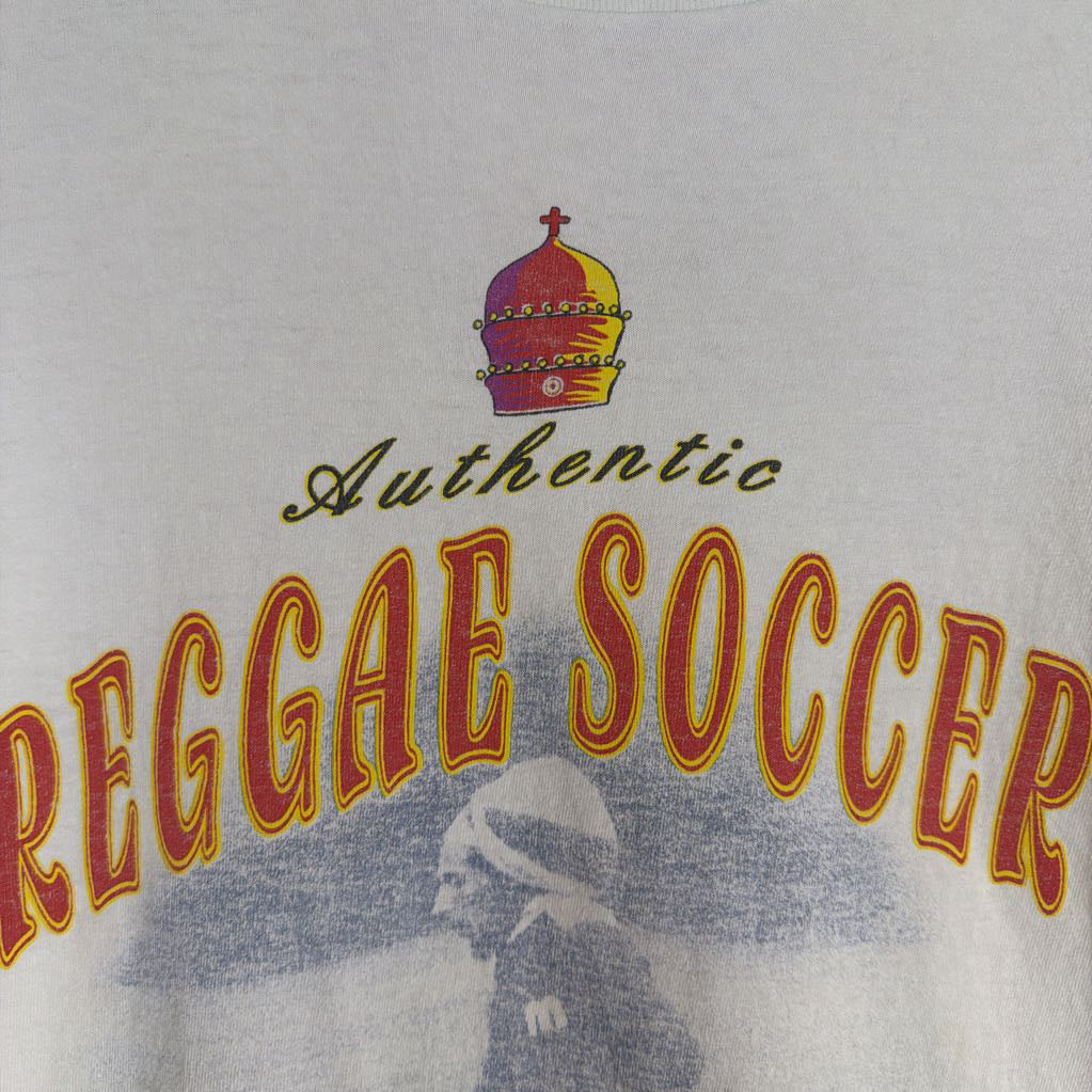 T-shirt with 'Authentic Reggae Soccer' text and crown logo on a light gray background