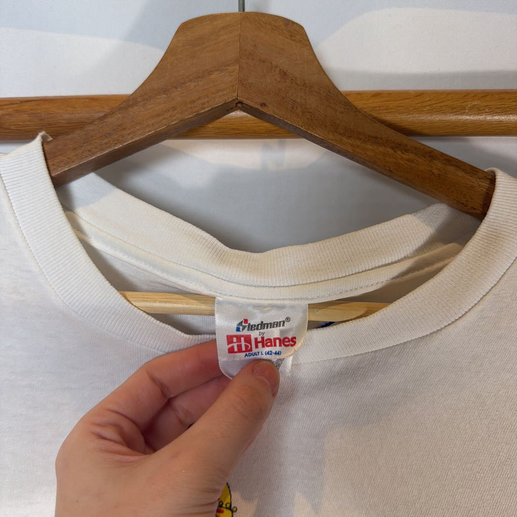 White t-shirt on a wooden hanger with a visible Hanes tag.